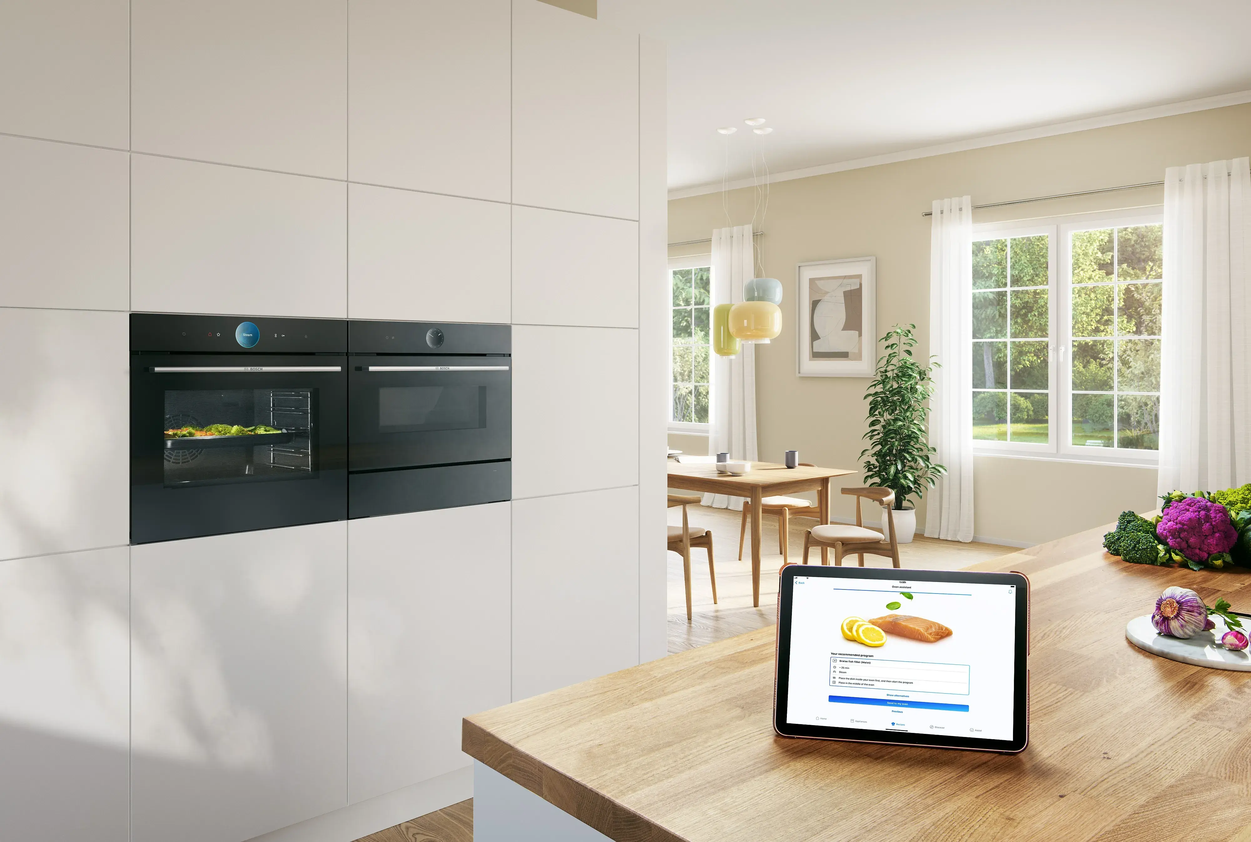 Bosch Einbauöfen schwarz in weißem Küchenhochschrank davor auf Küchentheke Tablet PC mit gestarteter Kochanwendung